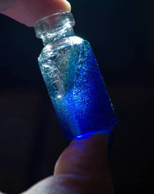 Mavi sihirli parlak sıvıyla el ele tutuşan şişe.