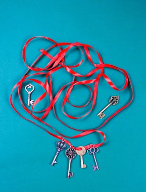 Koyu yeşil arka planda kırmızı atlas kurdelesi olan eski antika anahtarlar