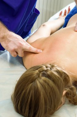 Erkek elinin yakın çekimi, kadının sırtına terapi masajı yapıyor.