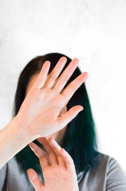 Elleri yüzünü kaplayan tanınmayan genç bir kadının portresi.