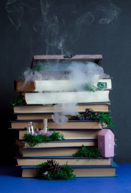 Kitapların üzerinde küçük şeylerin olduğu gizemli ahşap kutu. Yosun, karanlık arka planda buhar. Sihirli atmosfer