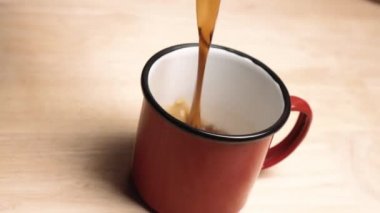 Koyu kahve fincana dökülüyor ve kamera açısını değiştiriyor..