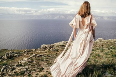 Çayırda beyaz elbiseli genç kız. Güzel bir uzun elbiseli bir çayır üzerinde poz kadın