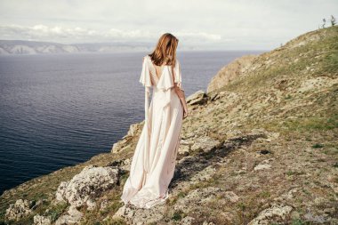 Çayırda beyaz elbiseli genç kız. Güzel bir uzun elbiseli bir çayır üzerinde poz kadın