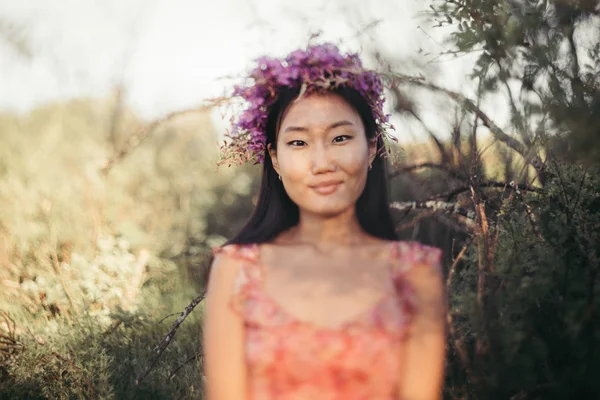 Gelukkig jonge vrouw in een krans van wilde bloemen en gras. Schattig meisje met zomerbloemen, close-up — Stockfoto