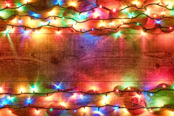 Luzes de Natal em um fundo de madeira. Decorações festivas brilhantes e coloridas de Ano Novo com luzes de Natal brilhantes. guirlanda colorida na mesa de madeira. leigos planos, vista superior, layout horizontal — Fotografia de Stock