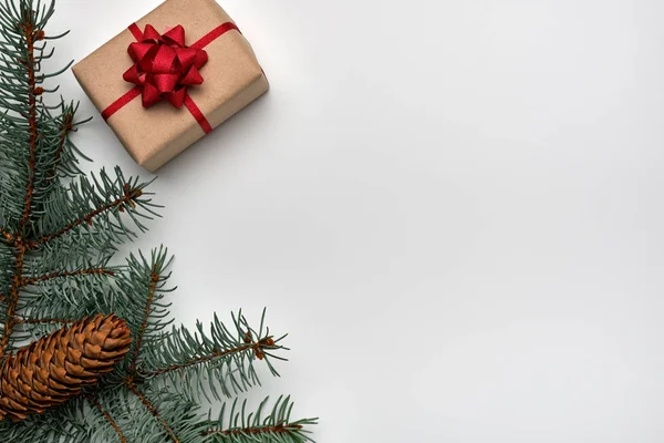 Рождественская или новогодняя композиция с подарочной коробкой, ветками елки и конусом ели на белом фоне. Копировальное пространство, плоская кладка, вид сверху — стоковое фото