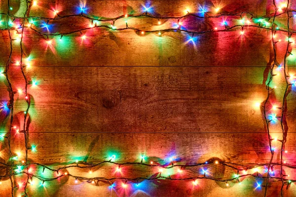 Quadro de luzes de Natal ou guirlanda colorida no fundo de madeira. Decorações festivas brilhantes e coloridas de Ano Novo com luzes de Natal brilhantes. Colocação plana, vista de cima — Fotografia de Stock