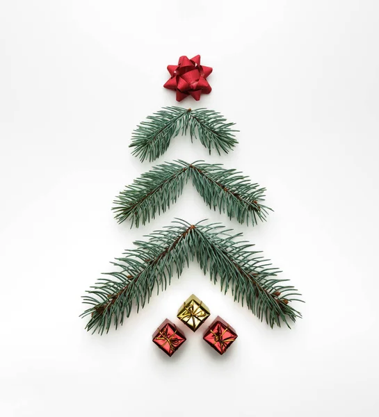 Stylized Christmas tree made of fir branches with gift boxes on white background. Flat lay, view from above — Stock Photo, Image