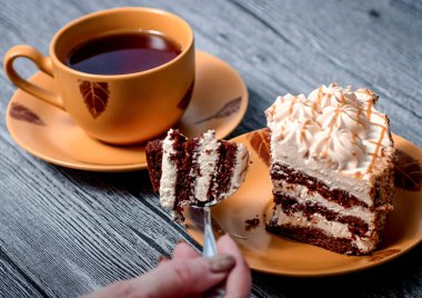 Kek yiyip ahşap bir masaya otururken çay içmeyi adam