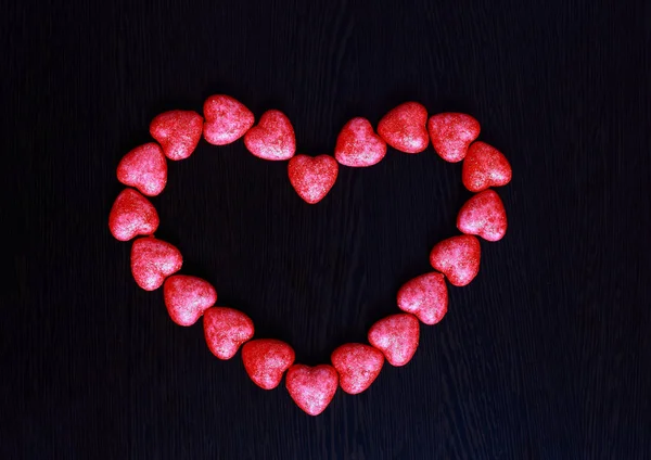 Rotes Herz aus kleinen Herzen auf dunklem Hintergrund Nahaufnahme. — Stockfoto