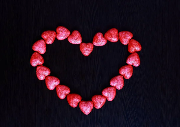 Cuore rosso fatto di piccoli cuori su uno sfondo scuro primo piano . — Foto Stock