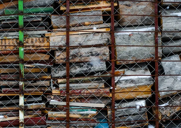 Una pila de madera de colores y tablones para horno rústico escondido detrás de la malla de alambre —  Fotos de Stock