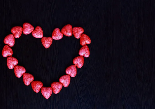 Corazón rojo hecho de corazones pequeños sobre fondo oscuro, primer plano, concepto de San Valentín — Foto de Stock