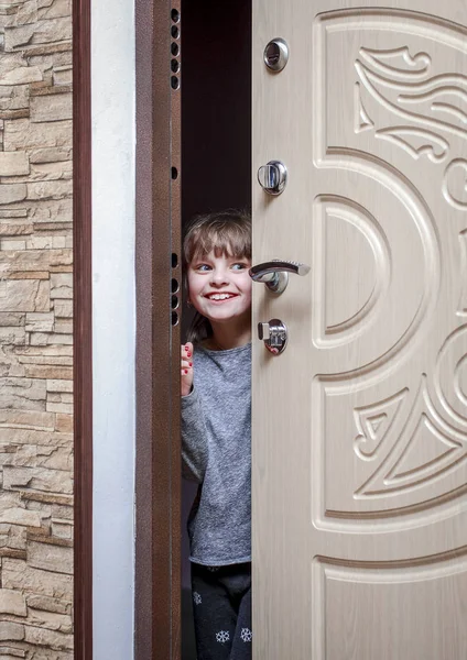 Маленька весела дівчинка відкриває двері квартири надворі і сміється — стокове фото