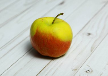 Bir elma ışık ahşap bir masa üzerinde yatıyor