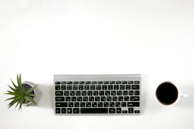 İş ofis yerinde. Beyaz arka plan üzerinde klavye ile kahve. Saksı.