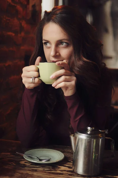 Beautiful woman sitting in the cafe, drink coffee and looking at the window. — Stock Photo, Image