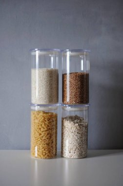  Gri arka planda cam kavanozlarda pişirilmemiş mısır gevrekleri.