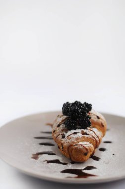 Çikolata ve böğürtlenli pudra şekerle kaplı kruvasan.