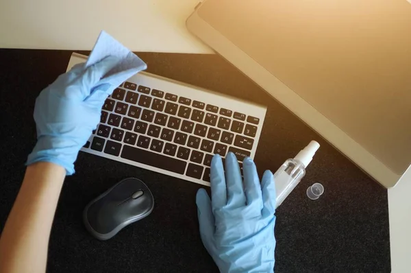職場でキーボード機器を消毒することで病気を防ぐ女性 — ストック写真