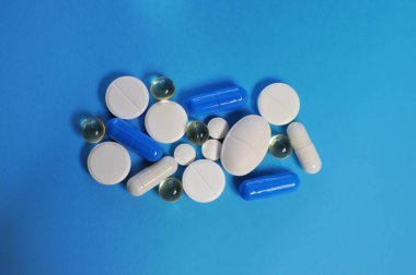 Mavi masada bir sürü farklı hap var. Bir sürü renkli hap, antiviral ilaçlar da dahil. COVID-19 ve diğer hastalıklara karşı ilaçlar