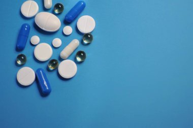 Mavi masaya farklı haplar serpiştirdim. Bir sürü renkli hap, antiviral ilaçlar da dahil. COVID-19 ve diğer hastalıklara karşı ilaçlar