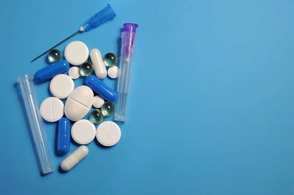 许多不同的药丸 蓝色桌子上有注射器 许多五颜六色的不同药丸 包括抗病毒药物 预防Covid 19和其他疾病的药物 — 图库照片