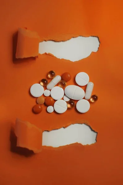 オレンジのテーブルの上にカラフルな錠剤がたくさんあります Covid 19およびその他の疾患に対する治療 抗ウイルス薬を含むカラフルな異なる薬の多く — ストック写真