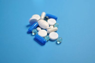 Mavi masaya saçılmış renkli haplar. Bir sürü renkli hap, antiviral ilaçlar da dahil. COVID-19 ve diğer hastalıklara karşı ilaçlar