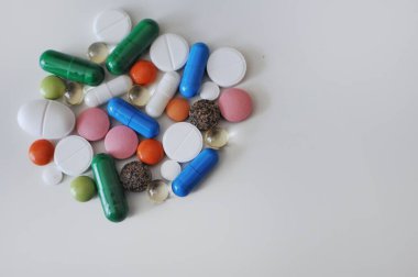Beyaz masada bir sürü farklı hap var. Bir sürü renkli hap, antiviral ilaçlar da dahil. COVID-19 ve diğer hastalıklara karşı tedavi