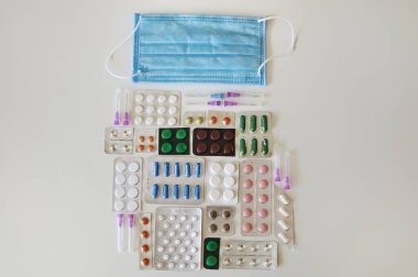 Masada bir sürü hap, şırınga ve maske kabarcıkları olan COVID 19 'a karşı tedavi seti