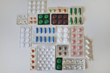 Beyaz masada farklı hapların kabarcıkları. Bir sürü renkli hap, antiviral ilaçlar da dahil. COVID-19 ve diğer hastalıklara karşı ilaçlar