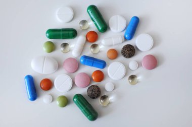 Beyaz masaya farklı haplar serpiştirdim. Bir sürü renkli hap, antiviral ilaçlar da dahil. COVID-19 ve diğer hastalıklara karşı ilaçlar