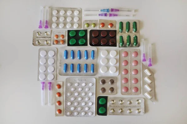 注射器と白いテーブルの上に多くの錠剤の複雑な水疱 抗ウイルス薬を含むカラフルな異なる薬の多く コロナウイルスやその他の疾患に対する治療 — ストック写真