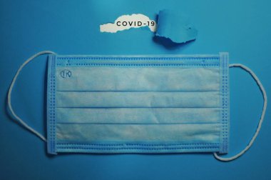 Mavi ilaç maskesi mavi arka planda ve modaya uygun başlıklı Yırtık kağıt altında Covid19