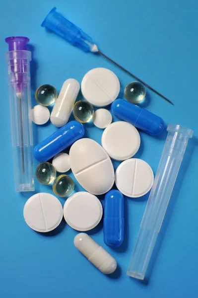Close up of colorful pills with syringe on blue table. Medicine against COVID-19