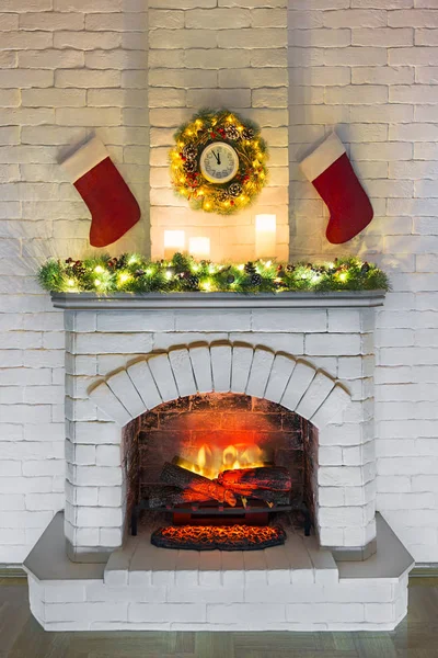 White fireplace with fire decorated for Christmas with candles,