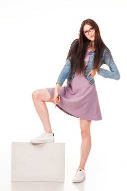 Genç güzel kız için reklam, posta beyaz arka plan ile poz logo. Pembe bir elbise ve denim ceket, spor ayakkabı ve gözlük giymiş. Uzun saçlı. Beyaz arka plan üzerinde izole fotoğraf.