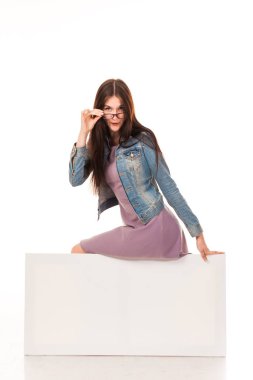 Genç güzel kız için reklam, posta beyaz arka plan ile poz logo. Pembe bir elbise ve denim ceket, spor ayakkabı ve gözlük giymiş. Uzun saçlı. Beyaz arka plan üzerinde izole fotoğraf.