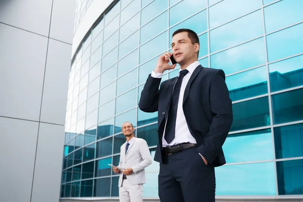 Homme d'affaires parlant au téléphone en arrière-plan du centre d'affaires, et d'autres hommes d'affaires — Photo