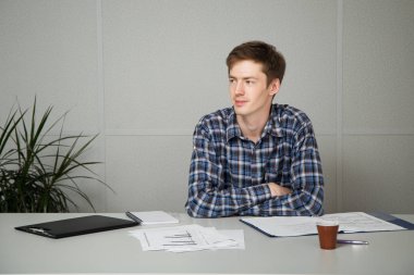 Ofis ve çalışma masasında oturan genç iş adamı