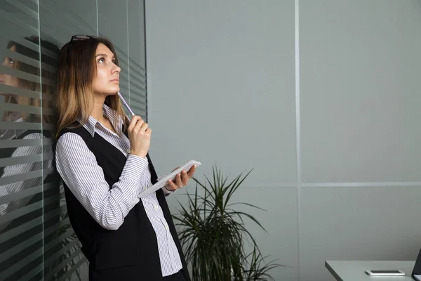 Junge Geschäftsfrau mit Brille in Freizeitkleidung, die am Tisch sitzt, schaut sich sorgfältig die Dokumente an — Stockfoto