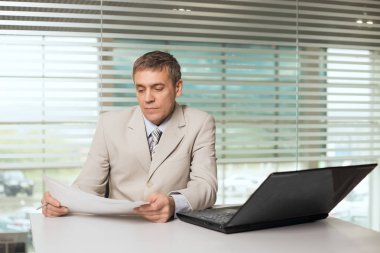 bilgisayar ve çalışma belgeleri ile ofis koltuğu oturan işkadını