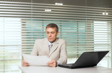 bilgisayar ve çalışma belgeleri ile ofis koltuğu oturan işkadını