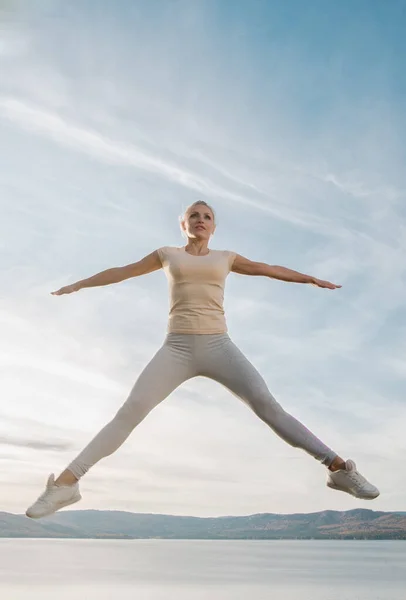 Vacker Kvinna Fitness Instruktör Hoppar Himlen Bakgrund — Stockfoto