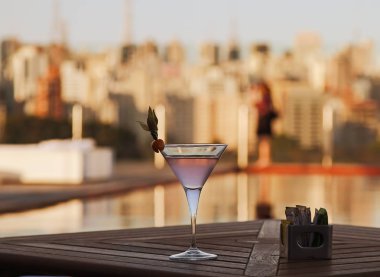 Şehrin arka planı ahşap bir masa üzerinde gül sıvı ile kokteyl cam