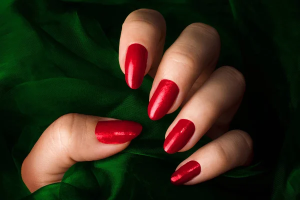 Červené nehty na zeleném pozadí — Stock fotografie