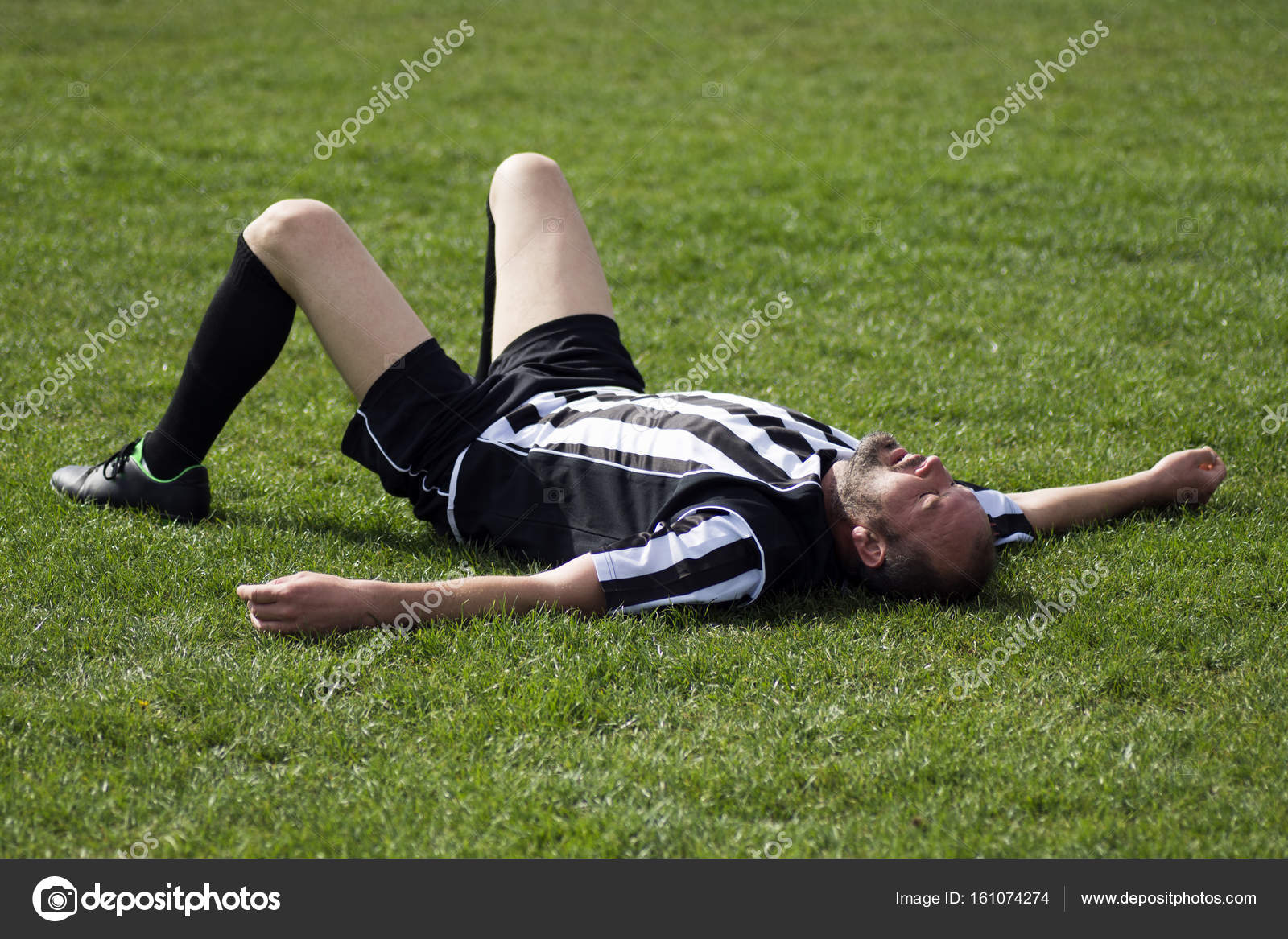Dois jogadores de futebol masculinos deitado na grama do campo