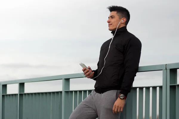 Jeune homme avec écouteurs utilisant le téléphone — Photo